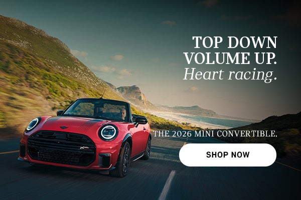 Red MINI convertible driving along a coastal road with mountains and ocean in the background, with advertisement text