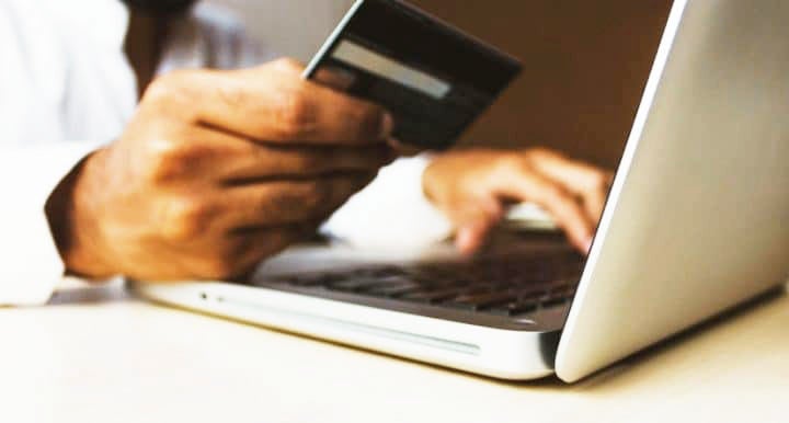 Hand holding credit card in front of open compute | MINI of Edison in Edison NJ