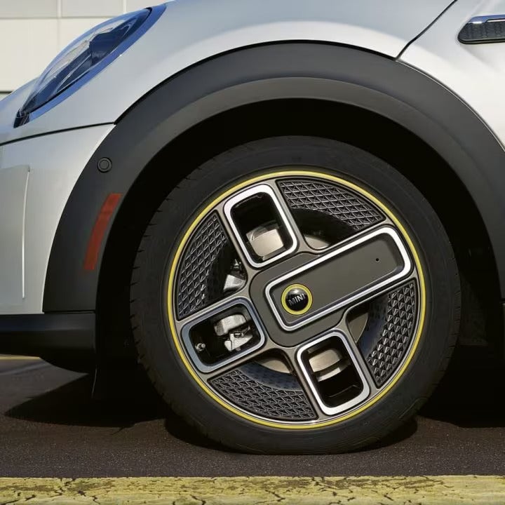 Closeup view of the front-left wheel on a MINI Electric vehicle parked on a street surface.