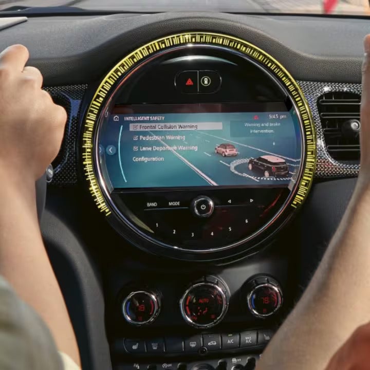 Closeup view of a black MINI steering wheel and dashboard from the perspective of a driver.